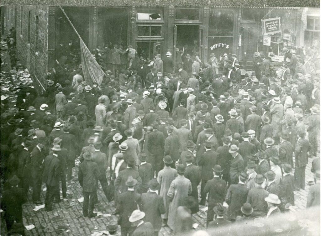 Crowd in uptown Butte looking at the Miner's Union Building after if was ransacked prior to the blast that blew it up on June 24, 1914. Butte, MT